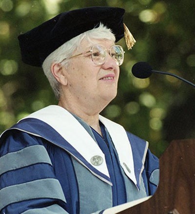 Vera Rubin in cap and gown outside in front of a podium
