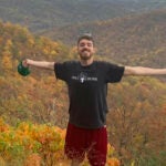 Dan O'Brien Standing with Open Arms  Among Orange and Green Leaves and Trees